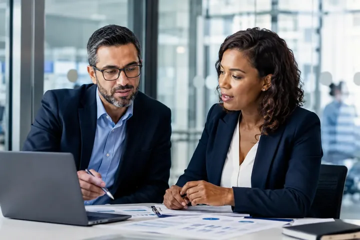 Two experienced clinical research professionals reviewing trial progress in a modern CRO or sponsor workplace